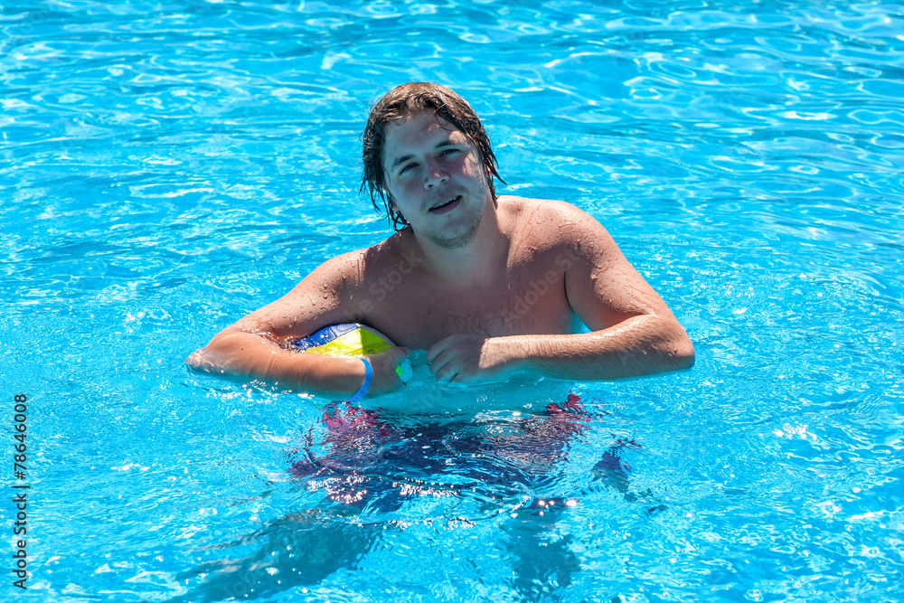 Happy man with water ball in a swimming pool