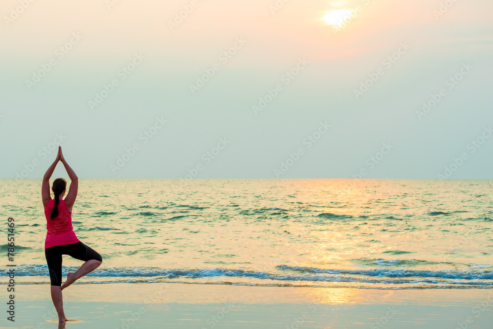 slender girl balancing on one leg. Yoga on the beach