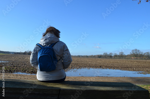 Woman resting from hike on bench in agricultural area © lembrechtsjonas