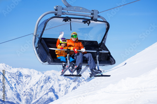 Boy and dad sit in chair lifting on the mountain