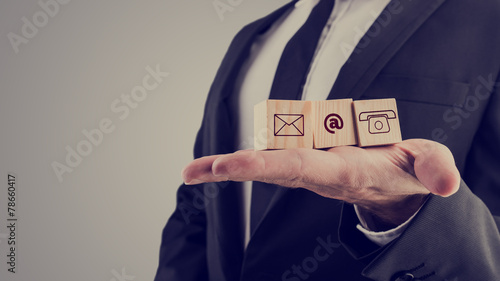 Businessman holding three wooden cubes with contact symbols photo