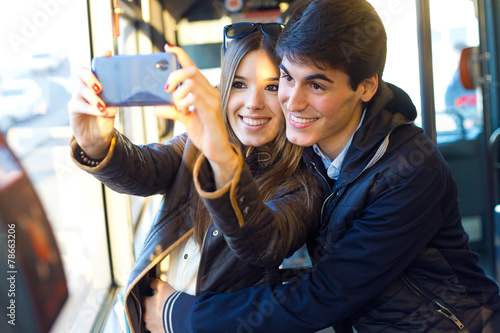 Young couple taking selfies with smartphone at bus.