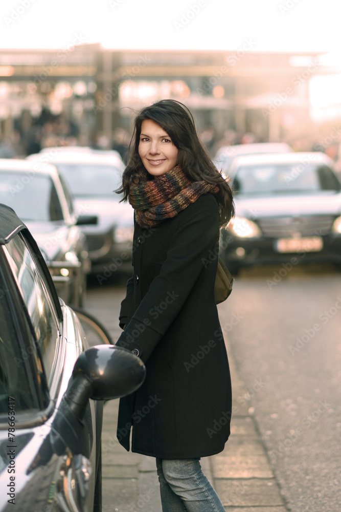 Modische Frau öffnet ihr Auto an der Straße Modische Frau öffnet ihr Auto an der Straße