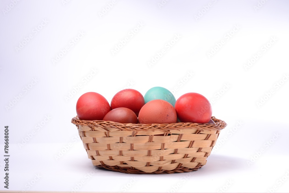 Naklejka premium Colored easter eggs in basket. White background.