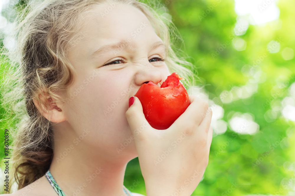 Little girl is eating ripe tomato Little girl is eating ripe tomato