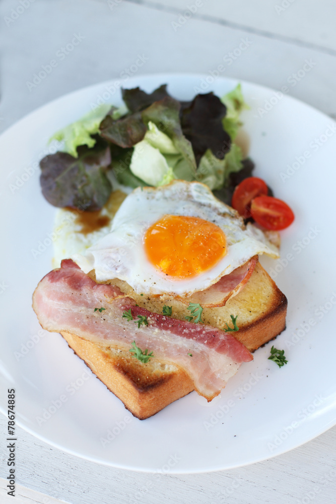 Plate of breakfast with fried egg, bacon and toast