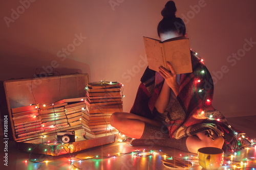 girl reading a book under blanket at home in cold weather