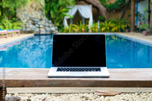Vacation work with laptop on bench at pool