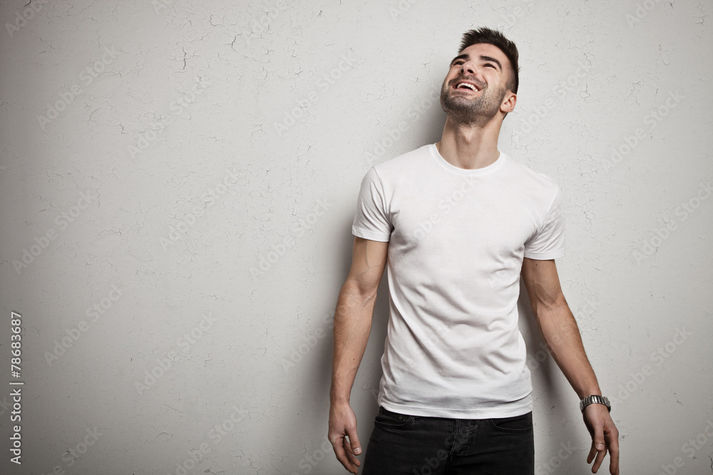 Smiling man in blank t-shirt, white grunge wall background Smiling man in blank t-shirt, white grunge wall background