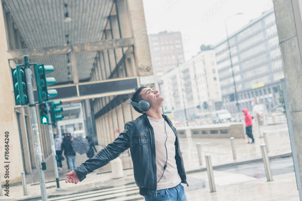 Young handsome man with headphones posing in the city streets Young handsome man with headphones posing in the city streets