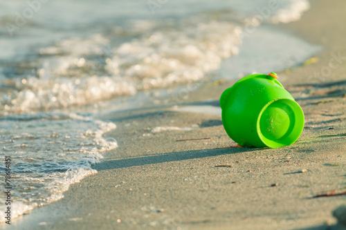 Toy bucket on a beach near the edge of the waves