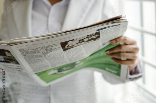 Business person reading newspaper in office