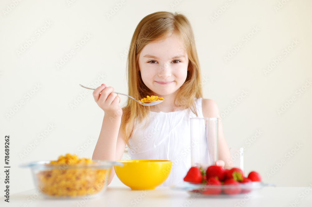 Adorable little girl eating cereal in a kitchen Adorable little girl eating cereal in a kitchen
