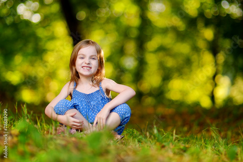 Cute little girl sitting on the grass on summer