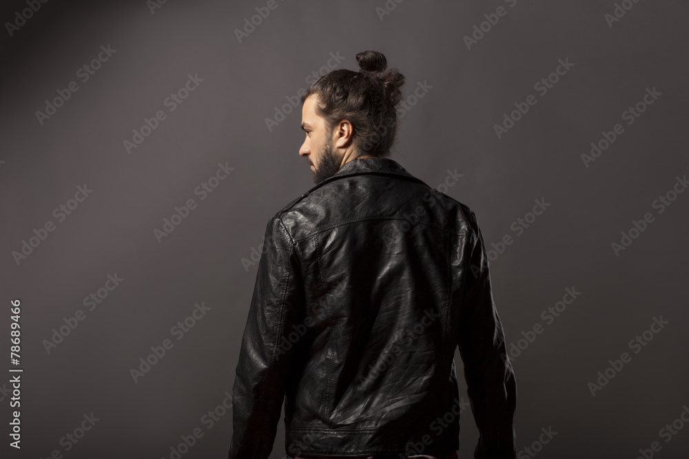 back view of man with beard and bun in black leather jacket Stock Photo
