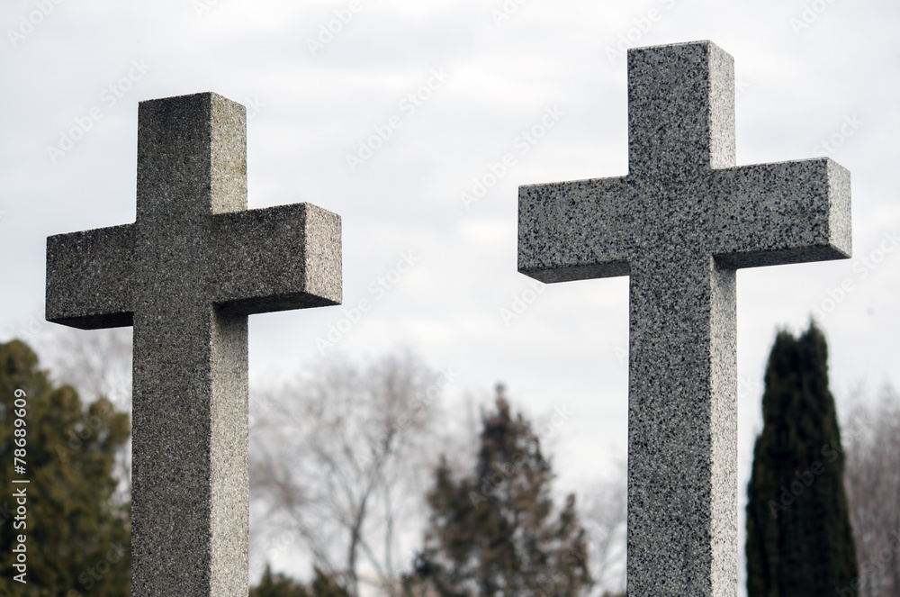 Two concrete crosses against sky and trees