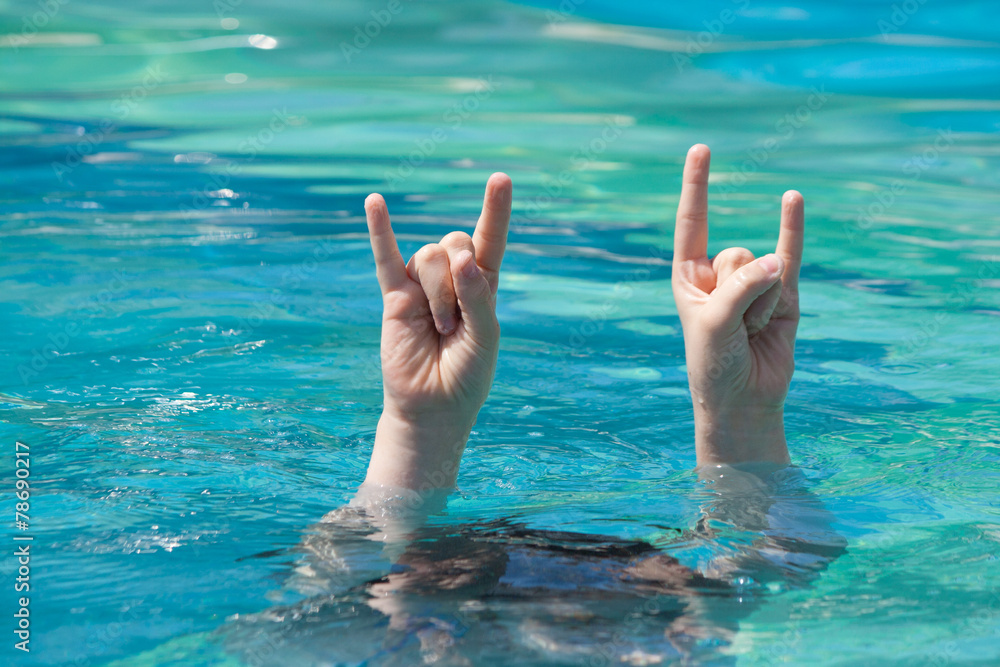 two hands out of water in rock gesture