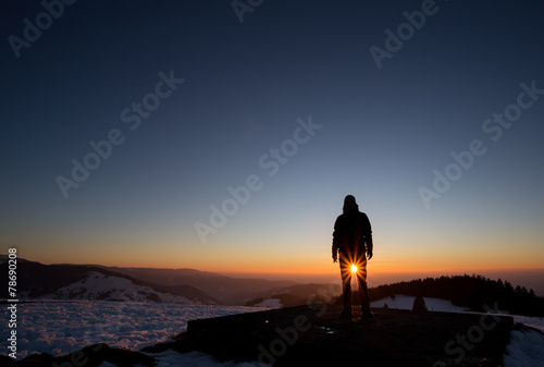 silhouetted man standing on mountain in sunset