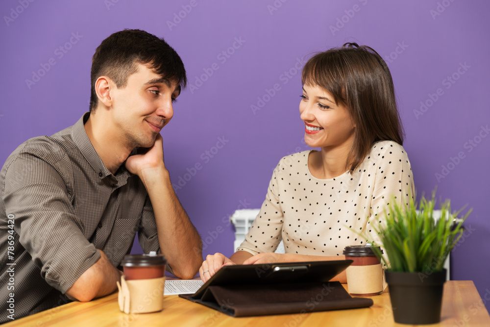 Young couple with tablet computer sitting at the table