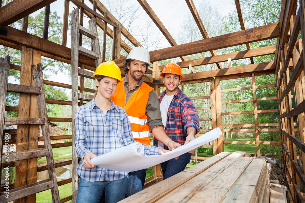 Confident Architects Holding Blueprint In Wooden Cabin Confident Architects Holding Blueprint In Wooden Cabin
