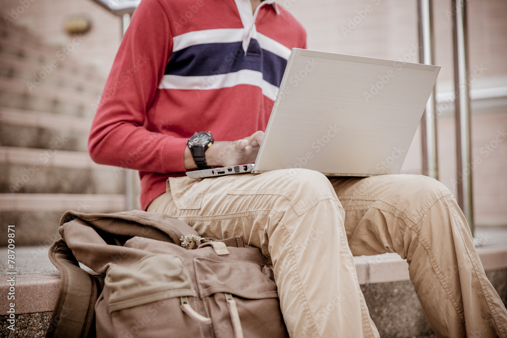 Obraz premium Young man using laptop on the steps