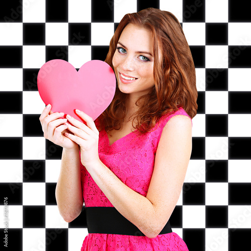 Beautiful young girl with heart in hands on checkered photo