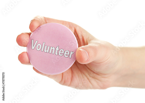 Round volunteer button in hand isolated on white