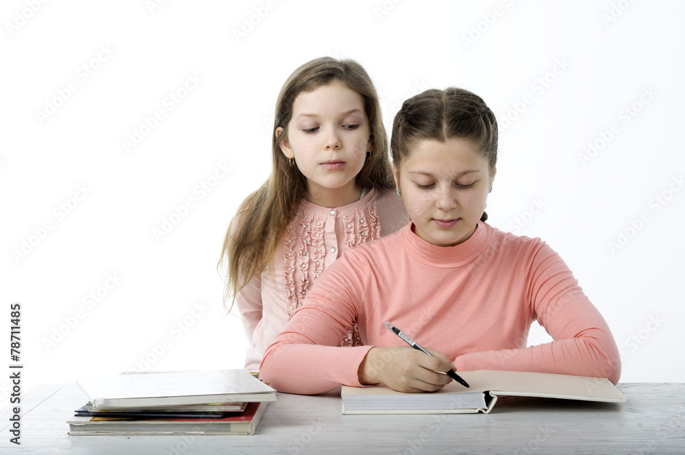 Little girls read books at the table on white Little girls read books at the table on white