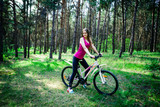 Young beautiful sports girl on a white bicycle in the woods