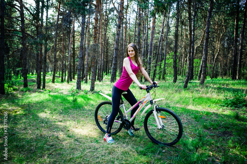 Young beautiful sports girl on a white bicycle in the woods © snike