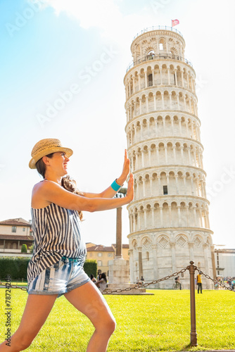 Obraz na płótnie Funny young woman supporting leaning tower of pisa, tuscany