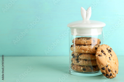 Leinwand Poster Tasty cookies in glass jar on color wooden background