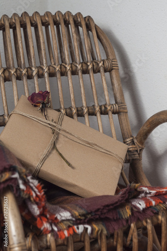 Present wrapped, decorated with a flower, on an old wicker chair photo