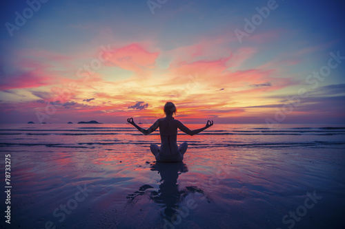 Woman doing meditation near the ocean beach.