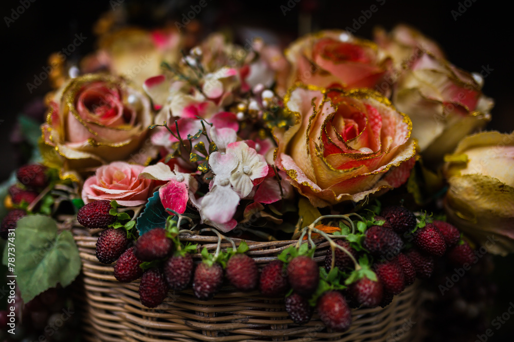 Obraz premium Artificial flowers in the basket over black background