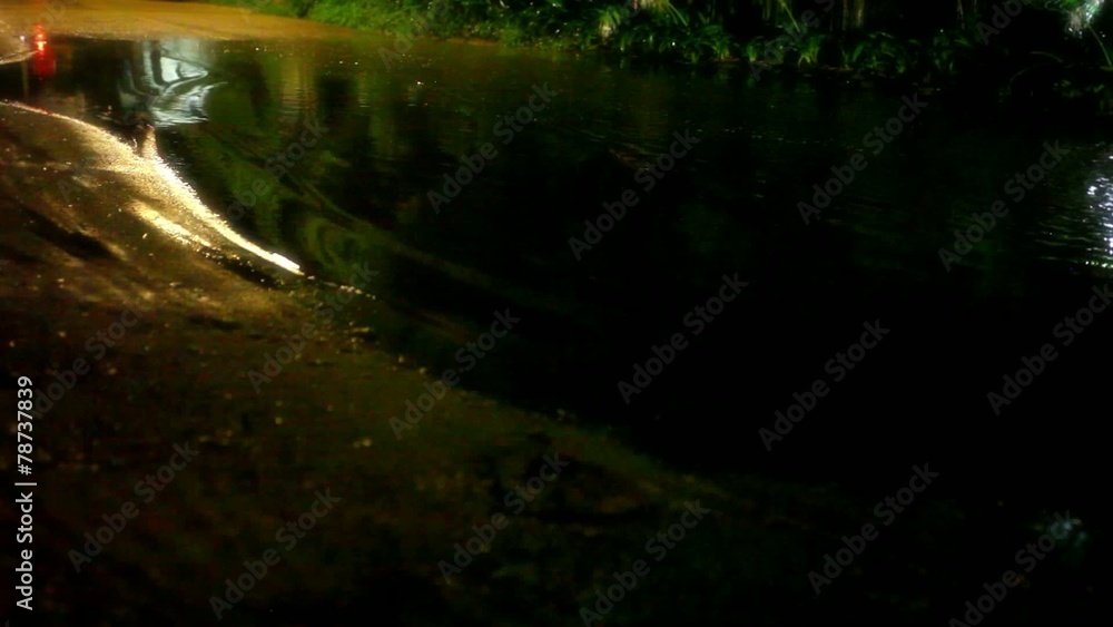 Motorbike drives through a puddle on the road at night after Motorbike drives through a puddle on the road at night after