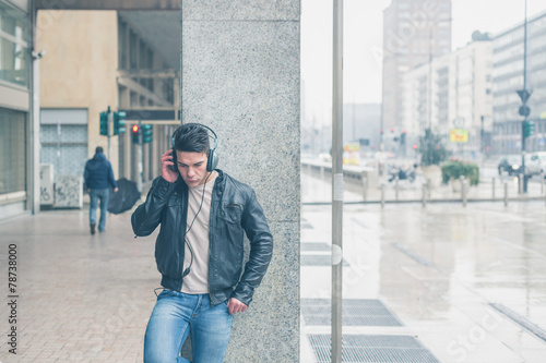 Young handsome man with headphones posing in the city streets