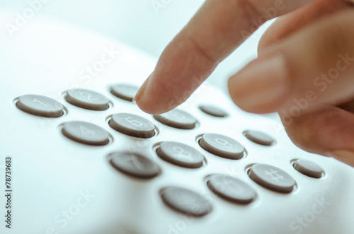 Woman finger dialling office telephone