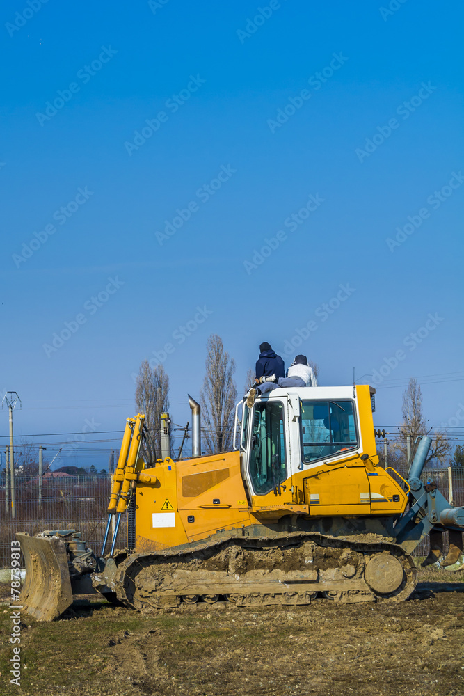 Two boys resting on top of yellow bulldozer