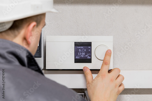 Engineer adjusting thermostat for automated heating system photo