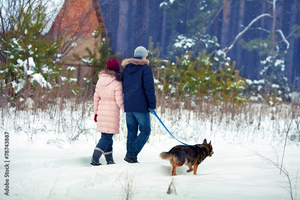 Young couple  with dog walking in the snowy village