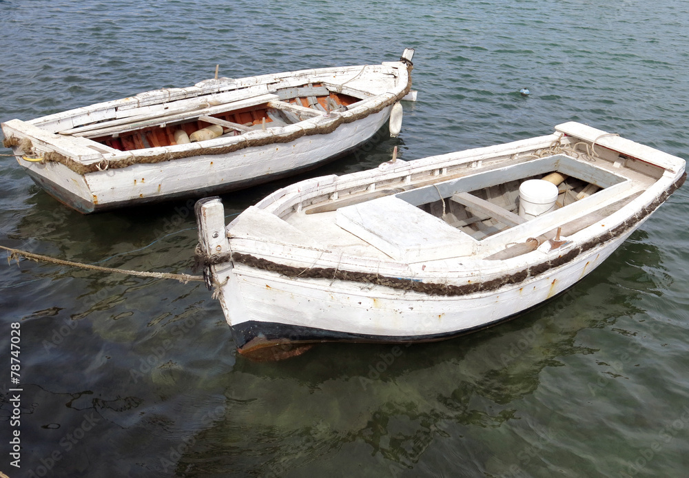 two white old boats in the middle of the water