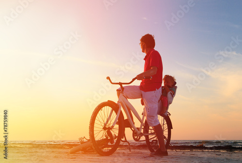 father and baby biking at sunset