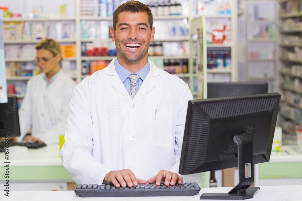 Happy pharmacist using computer