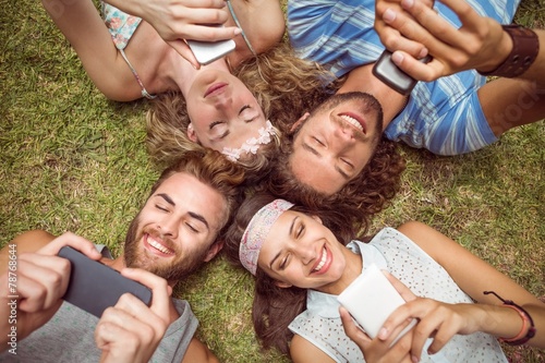 Hipsters lying on grass using smartphones