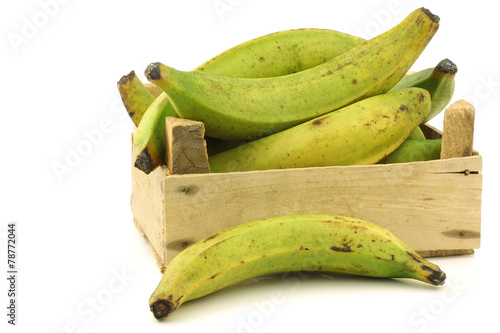 Foto unripe baking bananas (plantain bananas) in a wooden crate