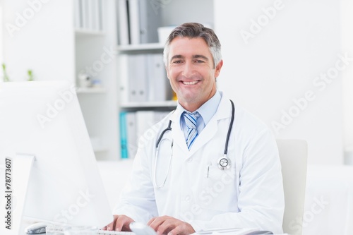 Confident doctor using computer in clinic