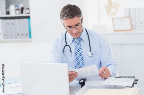 Doctor reading document at table