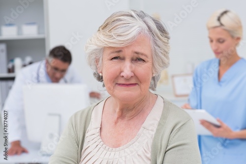 Unhappy patient with doctor and nurse working in background