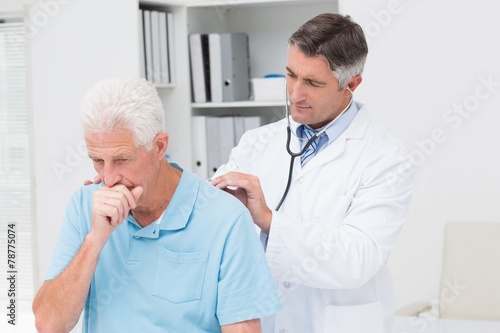 Doctor examining coughing senior patient photo